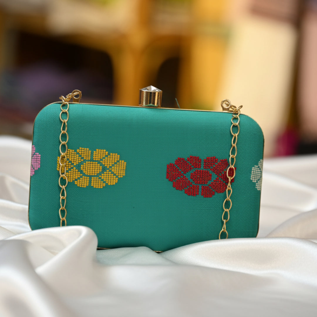 Teal handbag with floral patterns on a reflective surface